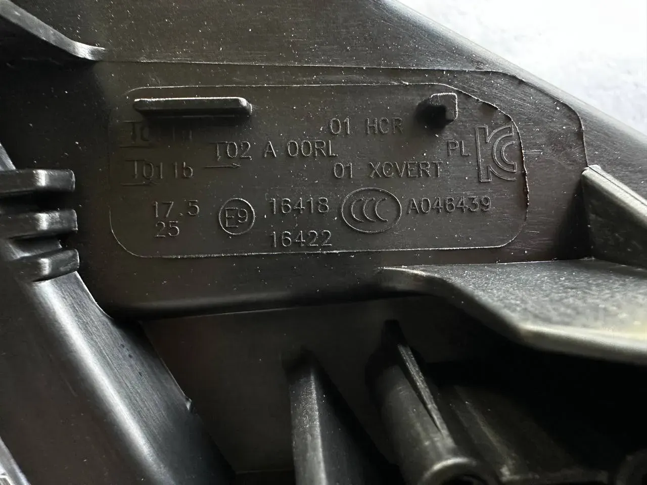 E-mark and function codes on headlamp lens — annotated close-up