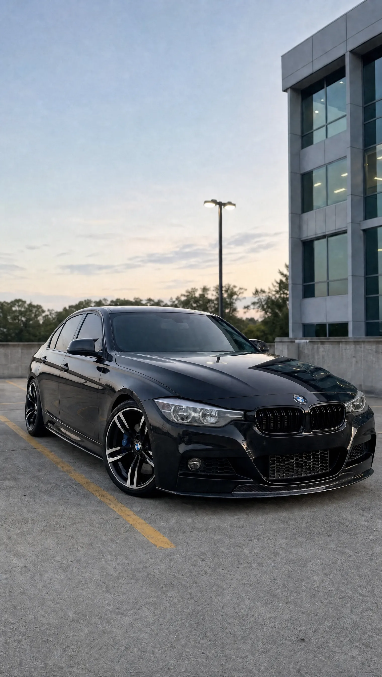 Schwarzer BMW F30 mit werkseitigen Halogenscheinwerfern in der Dämmerung – schwache Reflektoreinheiten, Ansicht schräg von vorn