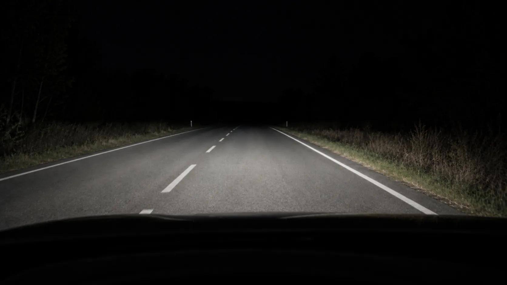 Fahrerperspektive mit korrekt eingestelltem Abblendlicht auf dunkler Straße — gleichmäßige Ausleuchtung im Nahbereich, scharfe Hell-Dunkel-Grenze und kein Licht über dem Horizont