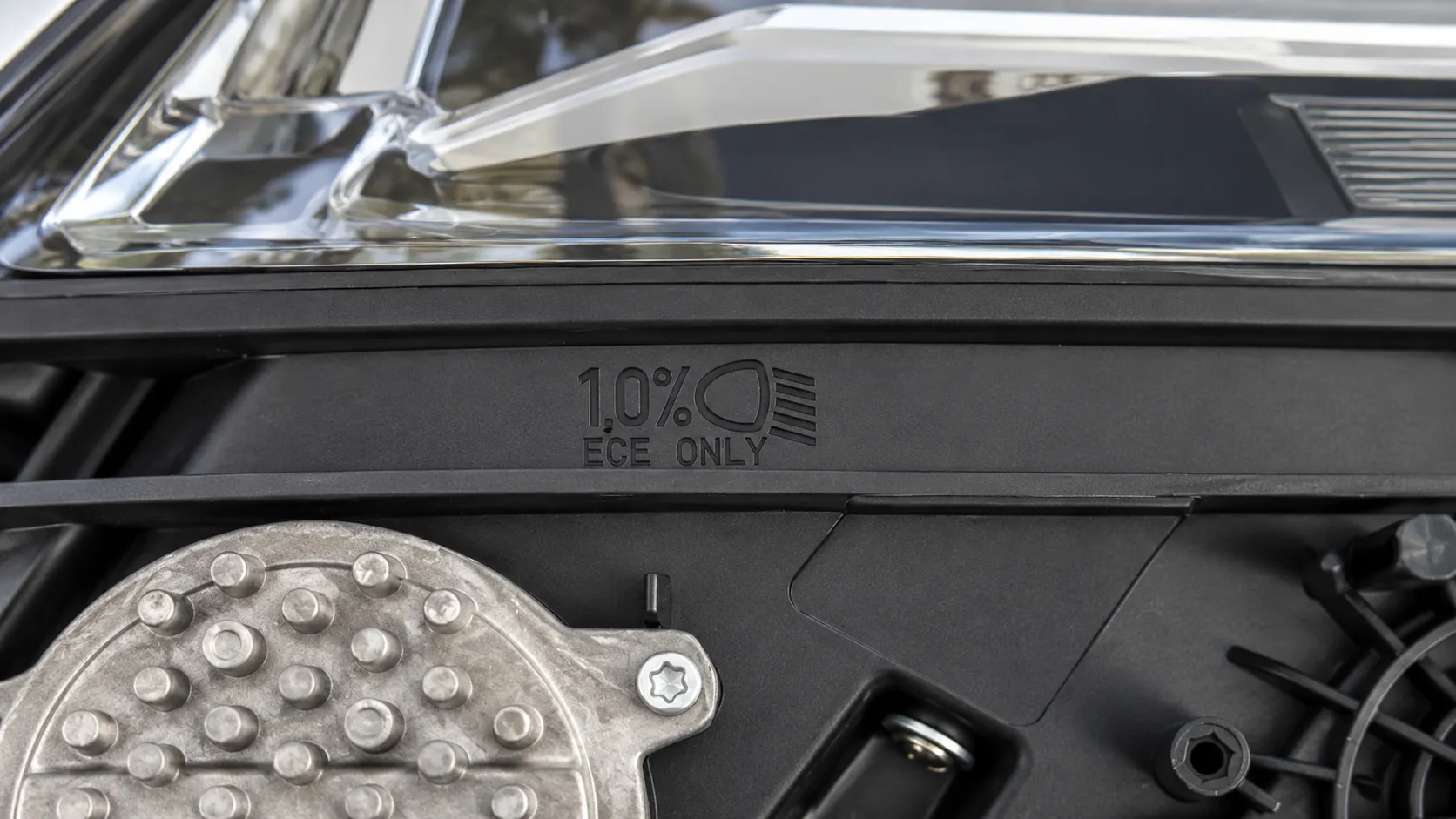 Rund um den Motorraum angebrachter Aufkleber zur Scheinwerfereinstellung mit Scheinwerfersymbol und vorgegebenem Neigungswert